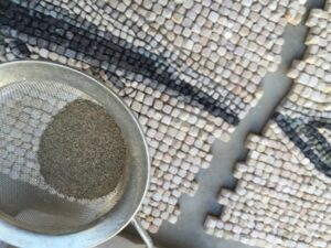 sieving a little bit of dry sand with a fine sieve over the mosaic in order to close the grout lines so that the cement can not fill the grout lines completely